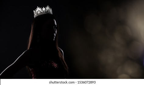 Portrait of Miss Pageant Beauty Contest in sequin Evening Ball Gown long dress with sparkle light Diamond Crown, silhouette low key exposure with curtain, studio lighting dark background dramatic - Shutterstock ID 1536072893