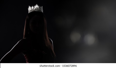 Portrait of Miss Pageant Beauty Contest in sequin Evening Ball Gown long dress with sparkle light Diamond Crown, silhouette low key exposure with curtain, studio lighting dark background dramatic - Shutterstock ID 1536072896