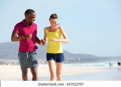 Portrait Of Mixed Race Couple Running Together On The Beach