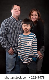 Portrait Of A Mixed Race Family With Mother Father And Young Son Over Black