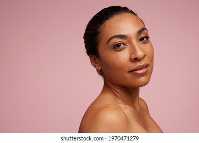Portrait of a mixed race woman with beautiful skin. Female model staring at camera over pink background.
