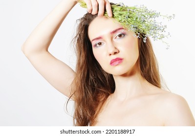 Portrait of a model with a bouquet of small blue wildflowers on white. Soft bright make-up. Cosmetics and nature concept - Shutterstock ID 2201188917
