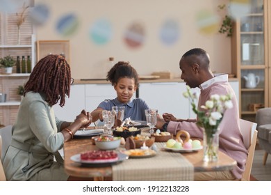 Portrait of modern African -American family enjoying dinner together while celebrating easter at home, focus on smiling teenage girl in center, copy space