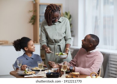 Portrait Of Modern African-American Woman Serving Food For Family While Enjoying Dinner Together In Cozy Home Interior, Copy Space