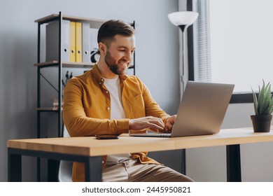 Portrait of a modern businessman man in a yellow shirt working on a laptop in the office - Powered by Shutterstock