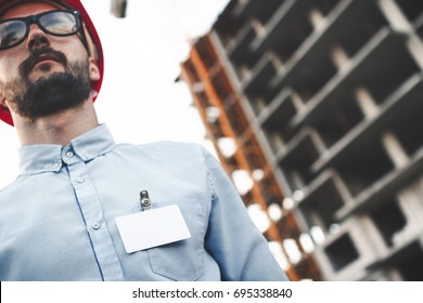 Portrait Of Modern Construction Engineer With White Blank Badge Or Name Card On Chest Of His Shirt On Background Of Construction Of Plant