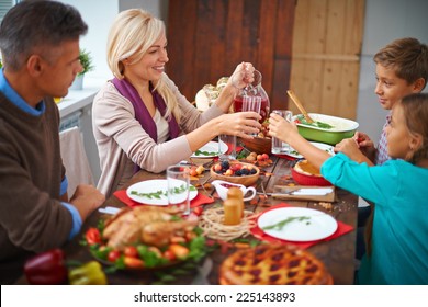 Portrait Of Modern Family Of Four Having Festive Dinner On Thanksgiving Day