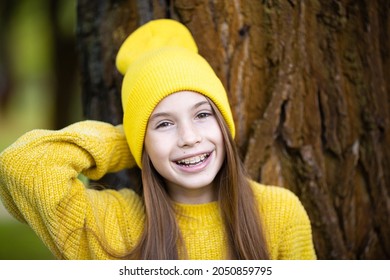 Portrait Of Modern Happy Teen Girl With Dental Braces Dressed In Yellow Clothes In Park. Pretty Teenage Girl Wearing Braces Smiling Cheerfully. Kid Girl In Autumn Smiling With Braces Teeth Apparatus.