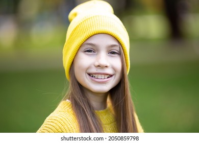 Portrait Of Modern Happy Teen Girl With Dental Braces Dressed In Yellow Clothes In Park. Pretty Teenage Girl Wearing Braces Smiling Cheerfully. Kid Girl In Autumn Smiling With Braces Teeth Apparatus.