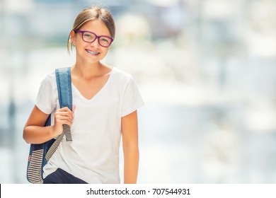 Portrait Of Modern Happy Teen School Girl With Bag Backpack. Girl With Dental Braces And Glasses.