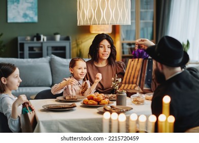 Portrait Of Modern Jewish Family Enjoying Dinner Together At Home And Playing Dreidel, Copy Space