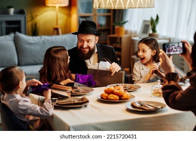 Portrait Of Modern Jewish Family Sharing Gifts At Dinner Table In Cozy Home Setting