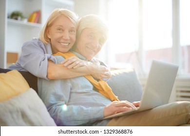 Portrait of modern senior couple embracing tenderly looking at camera in sunlight, copy space