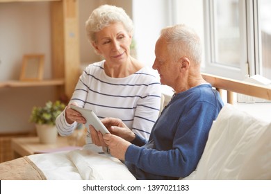 Portrait of modern senior couple using digital tablet sitting on bed in sunlight, copy space - Powered by Shutterstock