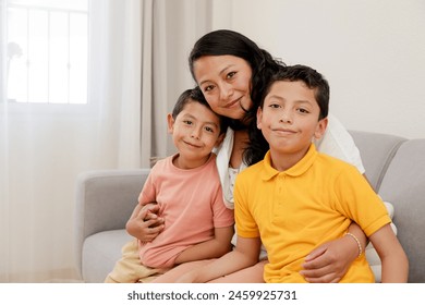 Portrait of mom and children at home-mom hugging hers two children in the living room of her house-single mother with her children-happy little family-Hispanic family - Powered by Shutterstock