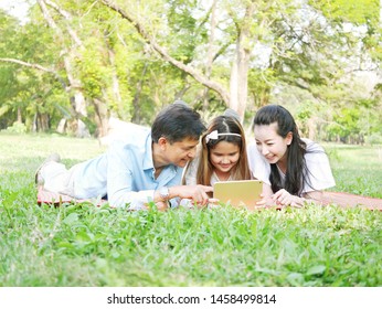 The Portrait Moments Of Happy Family Relaxing In The Park And Play IPad.