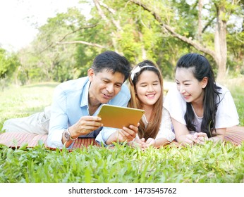 The Portrait Moments Of Happy Family Relaxing In The Park And Play IPad.