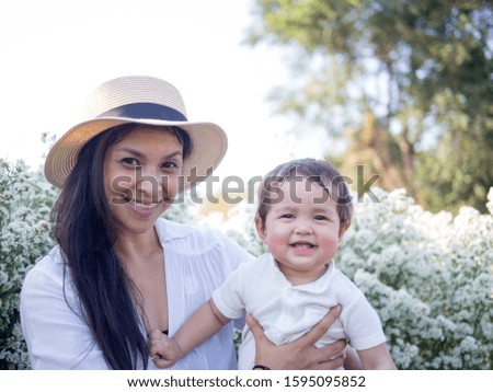 Portrait of mother and baby with big smile live together in the blooming garden.