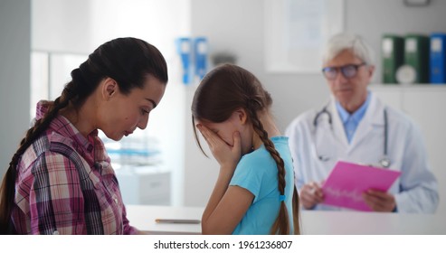 Portrait Of Mother Comforting Cute Little Girl Crying At Doctor Office. Scared Child Crying In Clinic Office Visiting Pediatrician With Mother. Healthcare And Medicine Concept