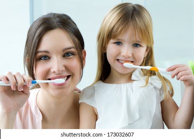 Portrait of Mother and daughter brushing teeth in the bathroom