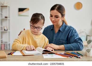 Portrait of mother and daughter with Down syndrome reading book together during adapted homeschooling lesson - Powered by Shutterstock