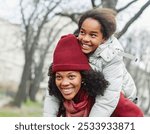 Portrait of mother and daughter having fun in park outdoors during autumn or winter,  family life, parenting, love and bonding concepts