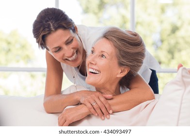Portrait of mother and daughter hugging. Happy senior mother and adult daughter embracing at home. Cheerful woman embraces older woman and looking at each other.