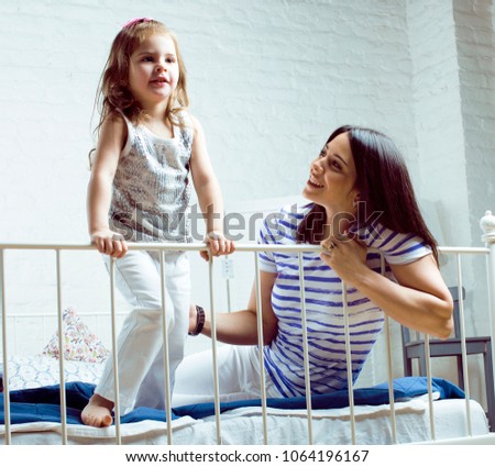 Portrait of mother and daughter laying in bed and smiling close 