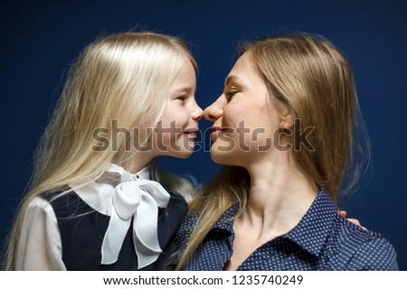 Portrait of mother and daughter on a blue background. White-skinned blondes. Close portrait at close range