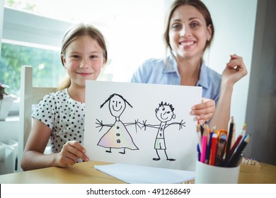 Portrait of mother and daughter sitting at table and daughter showing her drawing - Powered by Shutterstock