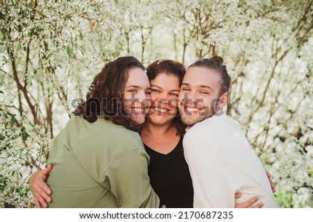 Two lesbian colombian women embracing and smiling in a park with greenery