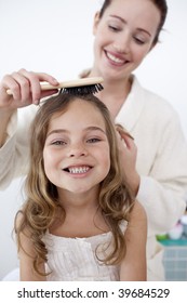 Portrait Of Mother Doing Her Little Daughter's Hair In Bathroom