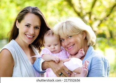 Portrait Of A Mother And Grandmother Smiling With Baby Outdoors