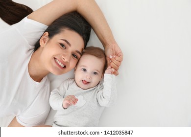 Portrait of mother with her cute baby lying on bed, top view. Space for text