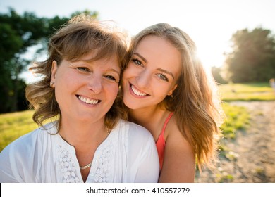 Portrait Of Mother And Her Teenage Daughter Outdoor In Nature With Setting Sun In Background