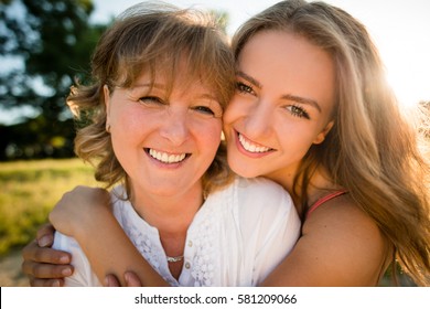 Portrait Of Mother And Her Teenage Daughter Outdoor In Nature With Setting Sun In Background