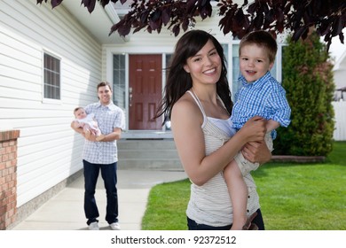 Portrait Of Mother Holding Her Son While Father Standing Behind Holding Baby