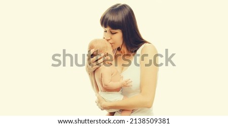 Portrait of mother kissing her infant on white background