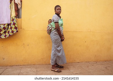 Portrait Of Mother And Son.African Woman Carrying Her Baby Boy On Her Back In A Street In Bamako,Mali.