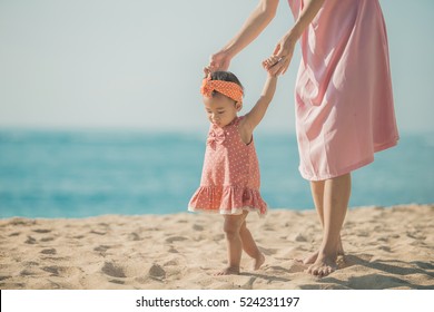 portrait of a mother is teaching her daughter walks on the beach - Powered by Shutterstock