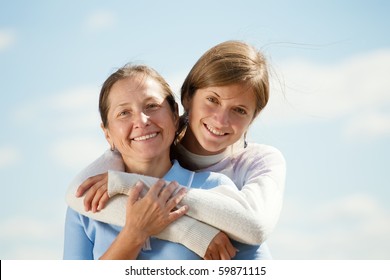 Portrait Of Mother With Teen Daughter Against Sky