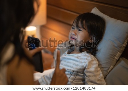 Portrait mother warning little girl not to more play game at smartphone