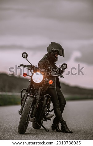 Portrait of motorcyclist woman using mobile phone, smartphone during stop. Young driver biker uses a navigator.