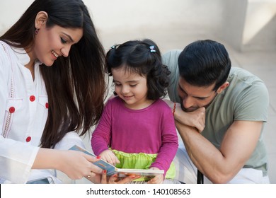 Portrait Of A Multi Ethnic Family In Outdoor, Mother And Reading A Story For Her Little Daughter.