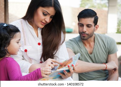 Portrait Of A Multi Ethnic Family In Outdoor, Mother And Reading A Story For Her Little Daughter.