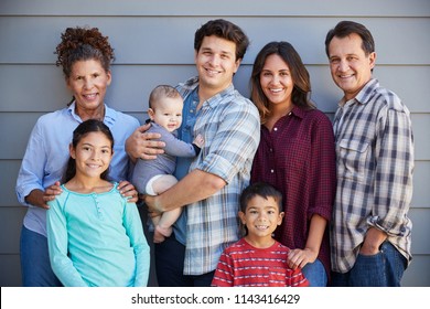 Portrait Of Multi Generation Family With Baby Standing Outside Grey Clapboard House