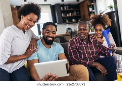 Portrait of multi generation family sitting in living room and using tablet pc - Powered by Shutterstock