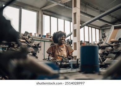 Portrait of multicultural female smiling graphic worker standing at printing workshop near screen printing press and printing on textile product. Happy diverse graphic technician working at workshop. - Powered by Shutterstock