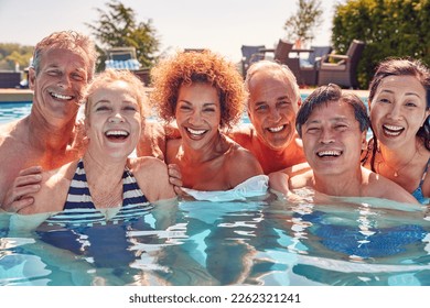 Portrait Of Multi-Cultural Group Of Senior Friends Relaxing In Outdoor Pool On Summer Vacation - Powered by Shutterstock