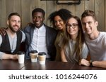 Portrait of multicultural millennial young friends looking at camera, happy multiracial people group having fun in coffeehouse together, diverse african and caucasian students bonding at cafe meeting